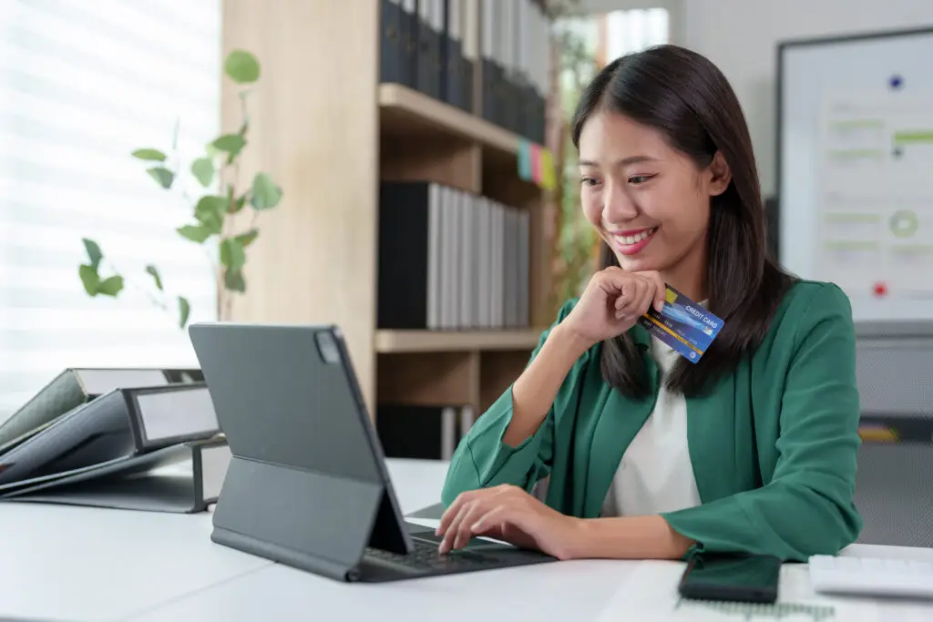 Asian businesswoman holding credit card, thinking about buying insurance