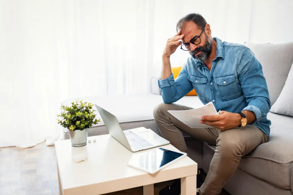 Confused frustrated mature man holding mail letter and money, reading shocking unexpected news nonsense in paper document, mad about high bill tax invoice, debt notification, bad financial report, money problem.